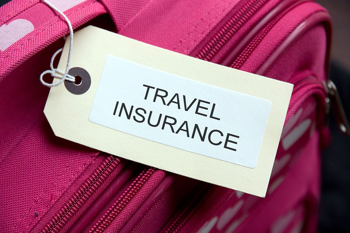A pink suitcase with the words travel insurance on it.