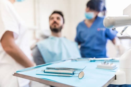 A man sitting in front of another man with dental tools.